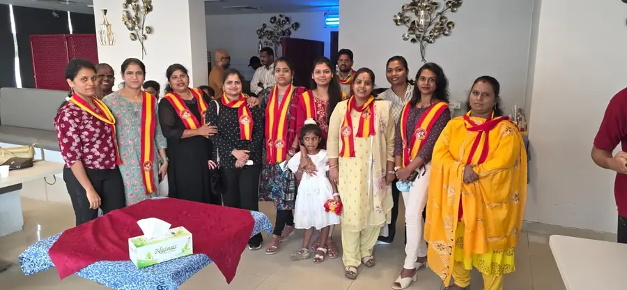 பிறந்தநாள் கேக் மேசையருகே நிற்கும் உறுப்பினர்கள்.