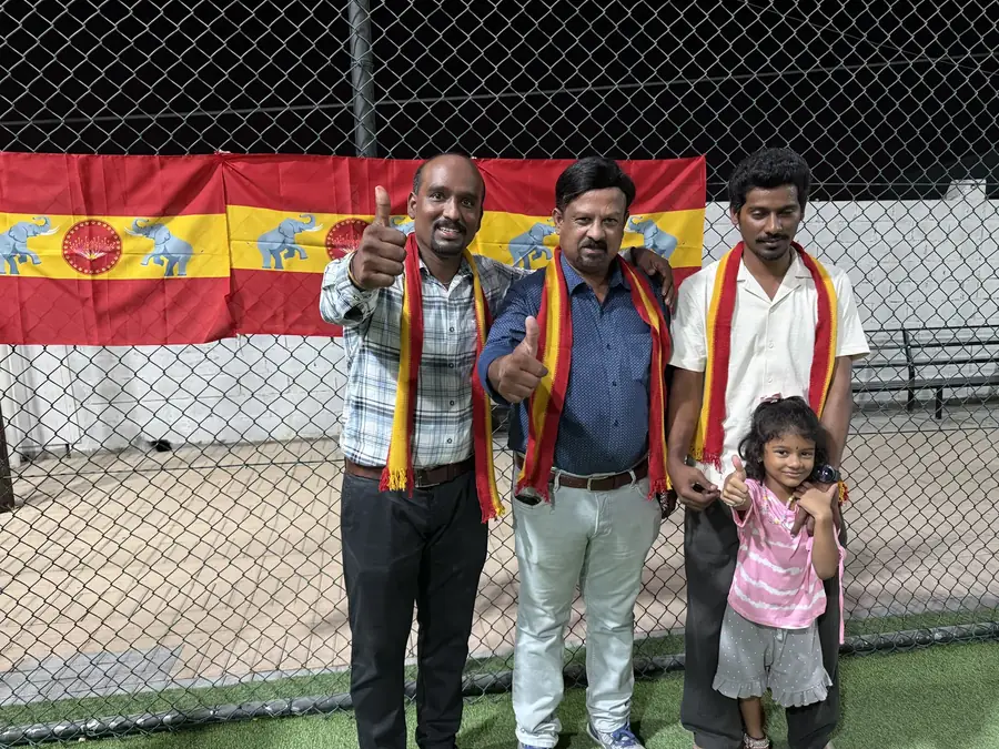 கொடி முன் நிற்கும் உறுப்பினர்களும் ஒரு சிறுமியும்.