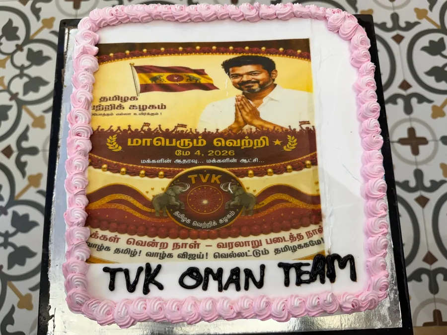 ‘TVK OMAN TEAM’ என எழுதப்பட்ட இரண்டாவது கேக் — மேலே கழகக் கொடியும் தலைவரின் படமும் பொறிக்கப்பட்ட வெற்றி வாழ்த்து.